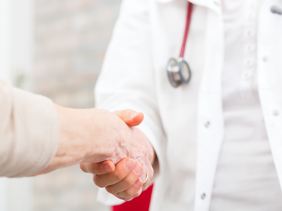 Arzt schüttelt älterer Patientin die Hand