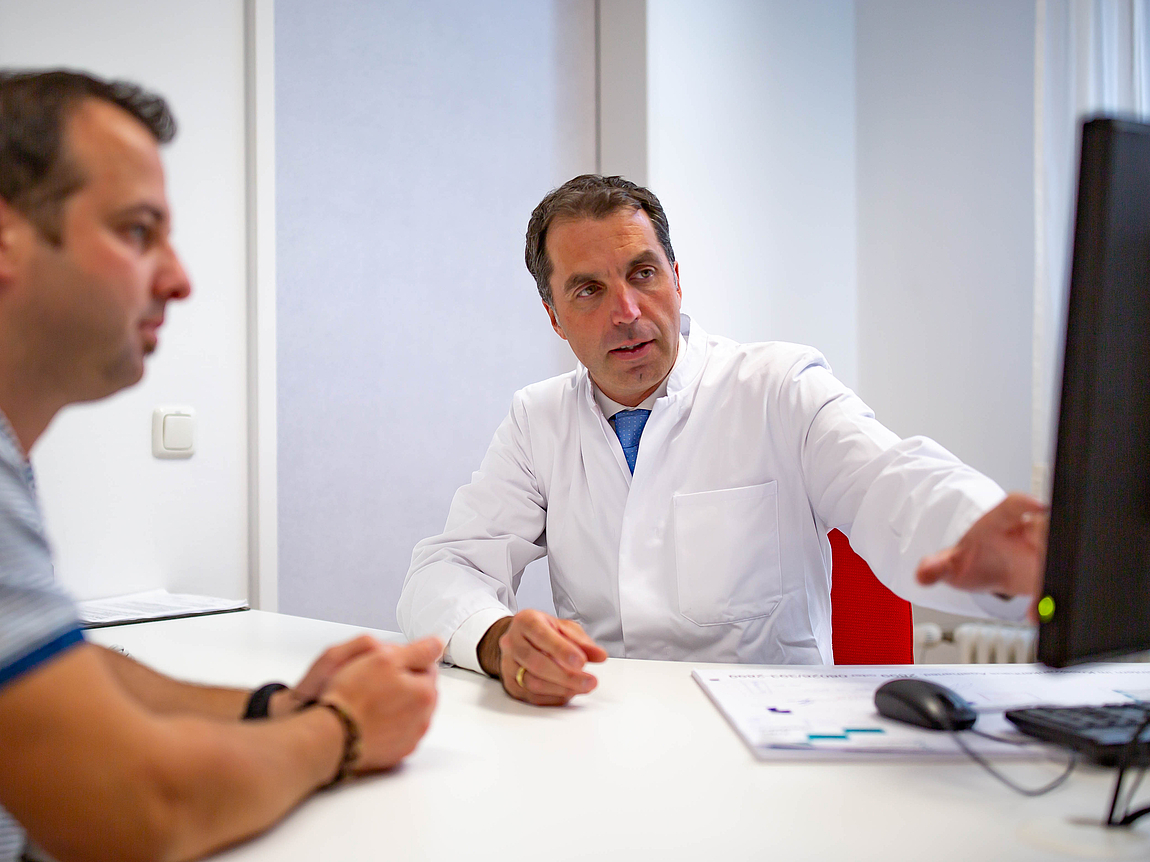 Arzt bei sportorthopädischer Beratung eines Patienten