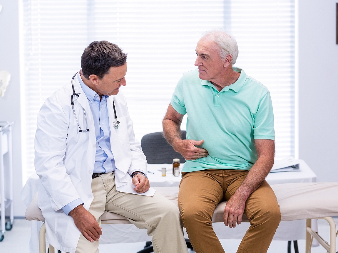 Patient zeigt Arzt schmerzende Stelle am Bauch